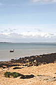 Motor boat and shingle beach at low tide in Gurnard on the Isle of White