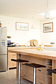 Barstools and chopping boards in light wood fitted kitchen in Isle of White home