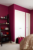 Black lacquered shelving unit in pink bedroom with built-in storage London home England UK