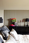 Floral patterned pillow with black sideboard in bedroom of Somerset barn conversion England UK