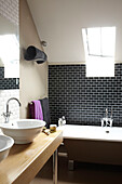 Schwarz gefliestes Badezimmer im Dachgeschoss einer umgebauten Scheune in Somerset, England, UK