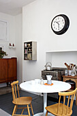 Wall mounted clock with circular pedestal base table in Scottish home UK