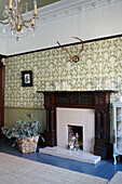 Patterned wallpaper and carved wooden fireplace in Scottish apartment building UK