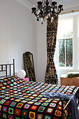Multicoloured bedspread and chandelier in Scottish apartment building UK