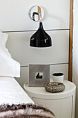 Black lampshade on wall sconce in contemporary Coombe bedroom, England, UK