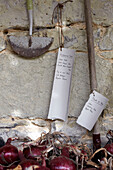 Gartenetiketten und Werkzeuge mit Zwiebeln an einer Wand in St Lawrence, Isle of Wight, UK