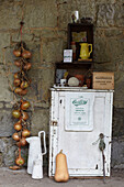 Onions hanging on stone wall with gardening cupboard in St Lawrence, Isle of Wight, UK