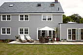 Gartenmöbel auf der Terrasse eines grau und weiß gestrichenen Hauses in Bembridge, Isle of Wight, England, UK