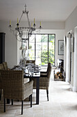 Dining table with wicker chairs and uncurtained picture window in Isle of Wight home, UK
