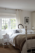 Weiß gestrichenes Schlafzimmer mit Bleiglasfenstern in einem Haus auf der Isle of Wight, UK