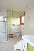 Steps to bath and glass shower cubicle in bathroom of Kent home, England, UK