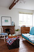 Tea tray on travelling chest in living room with turquoise sofa and exposed brick fireplace, Bembridge home, Isle of Wight, UK