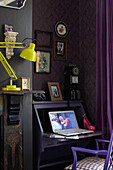 Laptop on purple desk with chair and yellow desk lamp in retro-styled London home, England, UK