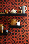 Vintage ceramics on black shelving with with patterned wallpaper in London home, England, UK
