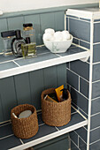 Cotton wool and perfume bottles with storage baskets in London bathroom, England, UK