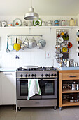Colanders and jugs hang above range oven with baking tray on gas hob in Ryde kitchen Isle of Wight, UK
