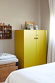 Family photographs on yellow cabinet with wall mounted shelf in Ryde bedroom Isle of Wight, UK