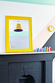 PLastic toys with yellow mirror frame clock and lamp on black mantlepiece in Hastings townhouse East Sussex England UK