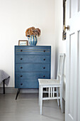Upcycled chair with blue chest of drawers in bedroom of Brighton home East Sussex UK