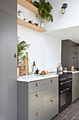 Open shelves above renovated kitchen with leather handles and range oven London UK