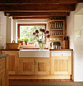 Modern country kitchen with wooden cupboards and butler sink with Alliums