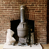 Potbellied wood burning stove in exposed brickwork fireplace