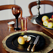 Gedeckter Tisch mit schwarzem Teller und geschnittenem Apfel