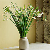 Stone vase with bouquet of snowdrops on table