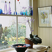 Sash window with row of colourful glass bottles and view to garden