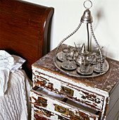 Detail of vintage bedside cupboard with middle eastern teaset and tray
