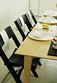 Gedeckter Tisch das Mittagessen mit Servietten und schwarzen Klappstühlen und Servietten im Esszimmer (Detailaufnahme)