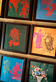 Detail of colourful framed Chinese silk fabrics with stencilled graphics
