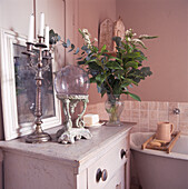 Bathroom corner with a display of eclectic objects on chest of drawers painted in white