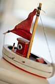 Small wooden toy fishing boat with a red sail