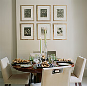 Gedeckter Tisch im Esszimmer für das Abendessen mit botanischen Drucken an der Wand im Hintergrund