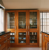 Cherry wood fitted kitchen units and a glass fronted dresser filled with dinnerware