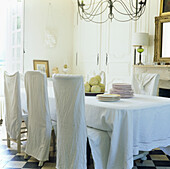 Dining chairs dressed with linen slip covers and an antique linen sheet is draped over the table