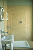 Modern white bathroom with walk in shower lined with beige mosaics