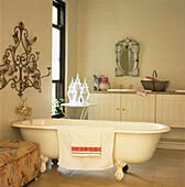 Roll top bath in elegant bathroom with Venetian mirror and decorative wall sconse