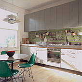 Green fibreglass shell chairs around table in modern fitted kitchen