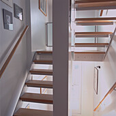 Modern open tread staircase in wood and aluminum, with reinforced glass panels on landings