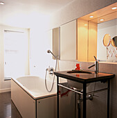 Weiße Wandmosaike in einem Badezimmer mit Badewanne, separatem Handwaschbecken und eingelassenem Spiegel