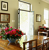 Bright pink flower arrangement in dining room with open door to garden