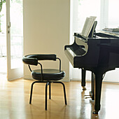 Close up of Le Corbusier stool in front of grand piano in bright living room
