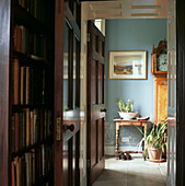 View of entrance hall with grandfather clock from the library lined with books