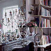 Kandelaber aus venezianischem Glas auf einem kunstvollen Marmorsims mit einem Bücherregal mit geschwungenen Fronten