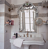 Venezianischer Glasspiegel über einem Handwaschbecken in einem elegant gefliesten Badezimmer