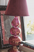 Nahaufnahme einer antiken Tischlampe aus rosa Glas mit dekorativem Rahmen