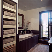 Gestreifte beige-weiße Handtücher auf Regalen im Badezimmer mit braun gebeizter Holzvertäfelung