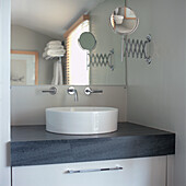 Close up of white ceramic sink bowl on grey marble with large mirror in modern bathroom 